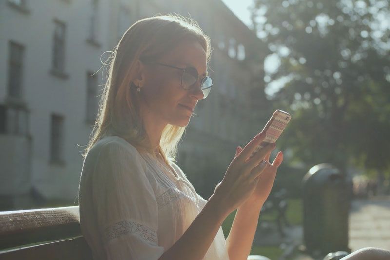 A woman looks at a phone. Are Wi-Fi Thermostats Cost-Effective?