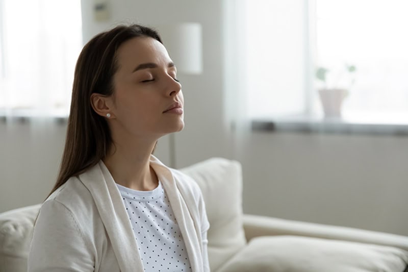 A young women holding her breath with her eyes closed.