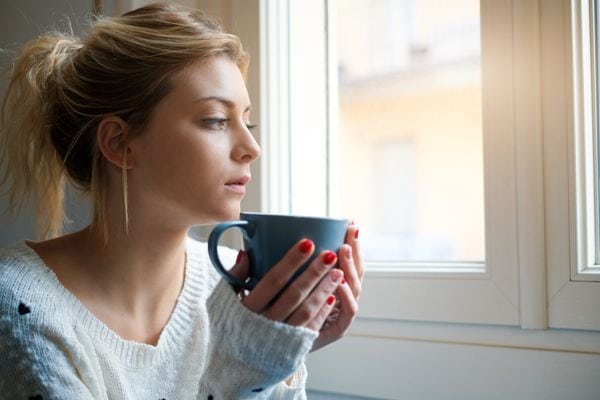 Image of someone drinking coffee or tea by a window. Why Won’t My Furnace Stop Running?