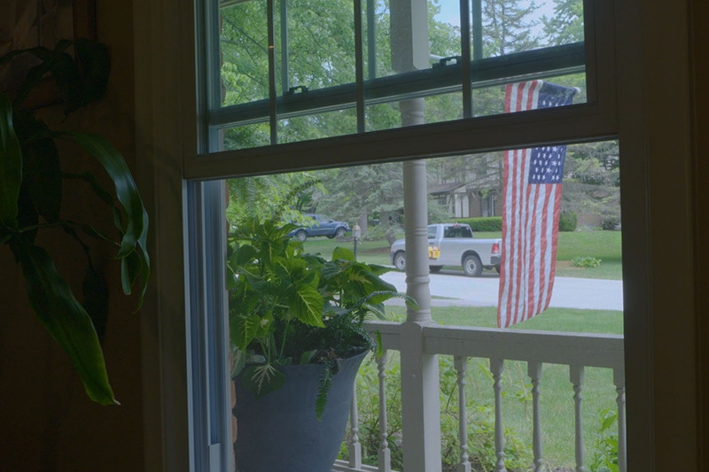 window looking out to a US flag in the front yard.