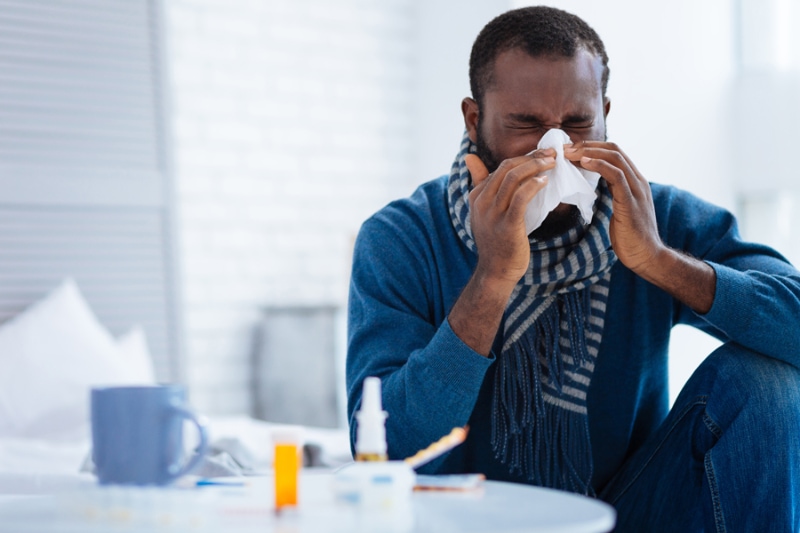 5 Signs Your Air Filter Has a Problem. Nice young ill man sitting in his comfortable room and sneezing.