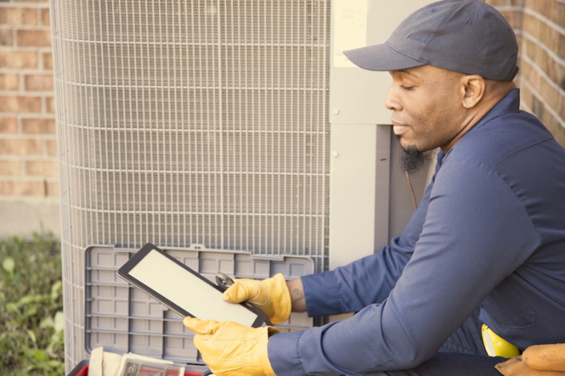 What Does an HVAC Maintenance Plan Provide. Blue collar air conditioner repairman at work.